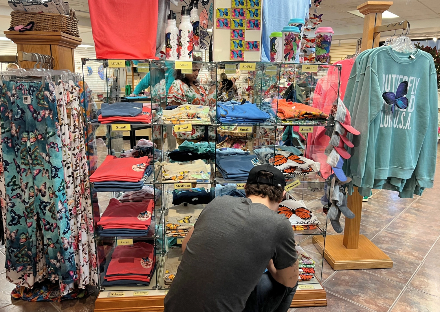 Photo of person looking at folded shirts on display at gift shop in Butterfly World Ft Lauderdale Florida