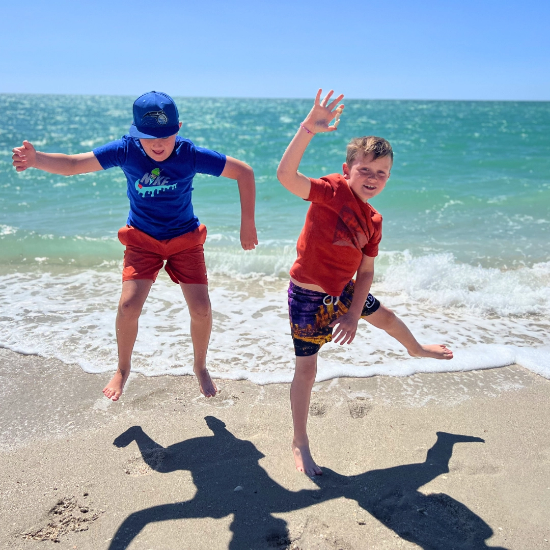 casey key boys jumping in front of the ocean in Southwest Florida